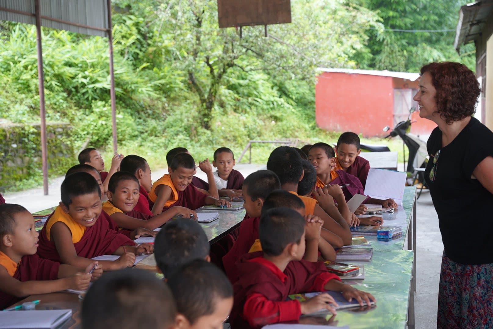 A White Woman With Monk Students In Classroom